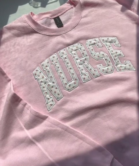 Pink shirt with 'NURSE' text on a light background
