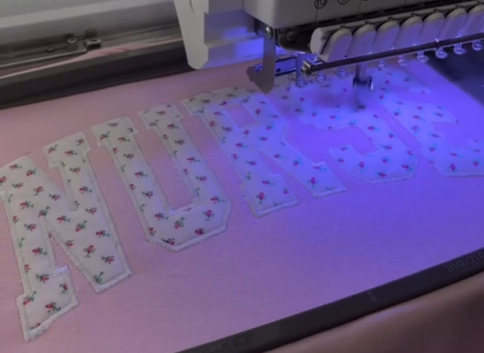 Embroidery machine working on fabric with letter patterns
